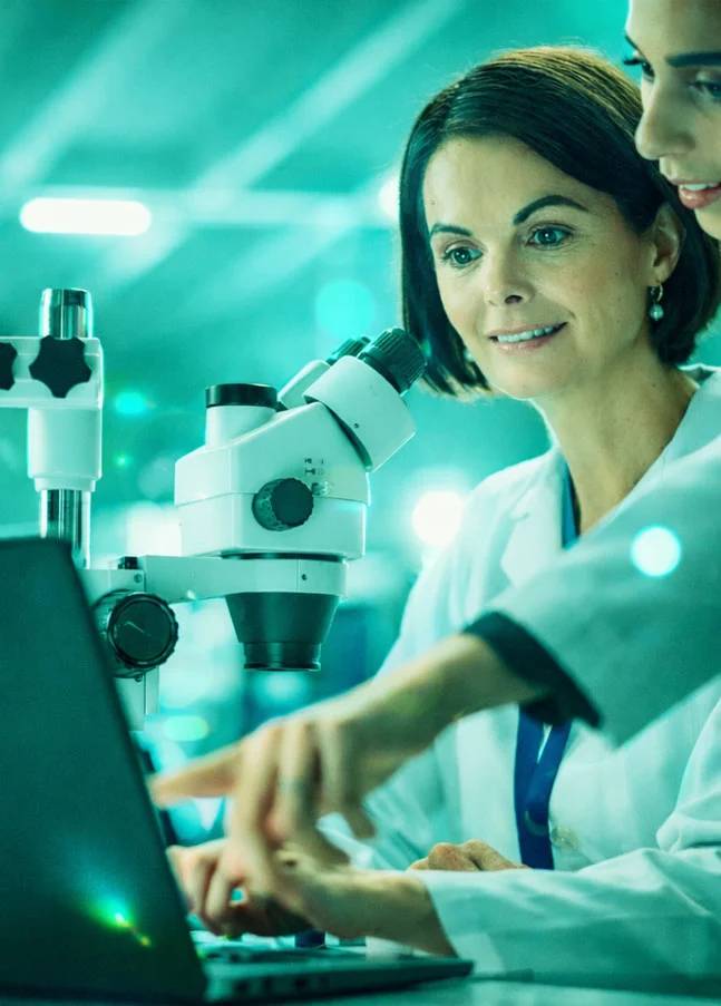 Wissenschaftlerinnen prüfen Labordaten am Computer – Beispiel für GxP-Compliance, CSV-Audits und Data-Integrity-Kontrollen.