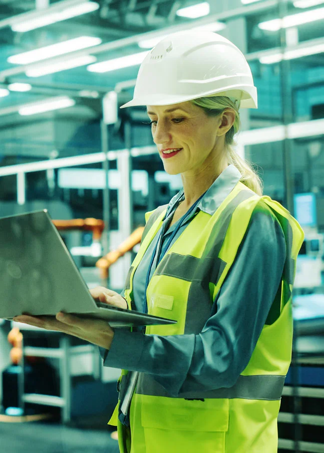 Ingenieurin nutzt Laptop zur Qualitätskontrolle in einer Produktion mit SAP Qualitätsmanagement